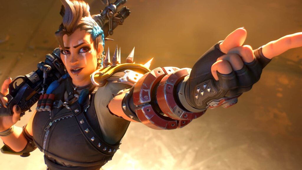 Junker Queen з Overwatch, впевнено вказуючи вперед, у шипованих обладунках і тримаючи свою рушницю на плечі.
